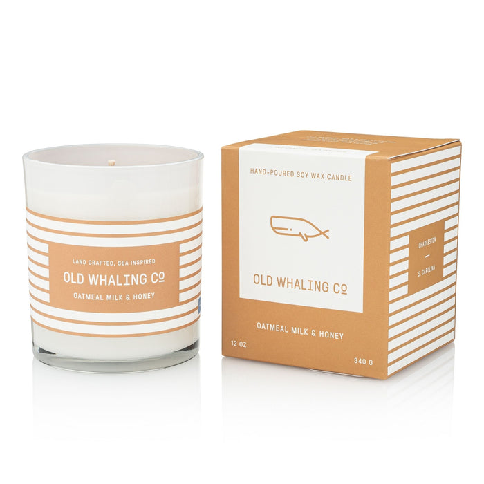 A hand-poured soy wax candle in a clear glass jar with a white label and peach stripes, shown next to its matching kraft paper box. The brand 'Old Whaling Co.