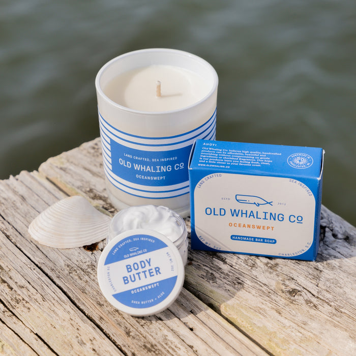 Oceanswept Candle, Soap, and Travel Size Body Butter on wood dock with ocean background