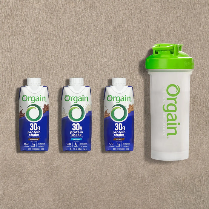 Orgain protein shake cartons and a shaker bottle on a beige background