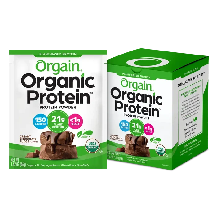 Orgain Organic Protein Powder in Creamy Chocolate Fudge flavor, shown as a single-serve packet alongside a 10-count carton. The packaging features green and white branding and highlights key product benefits, including 21g plant protein, 150 calories, less than 1g sugar, and USDA Organic certification. The product is displayed with chocolate fudge pieces and is labeled vegan, gluten-free, non-GMO, and soy-free.